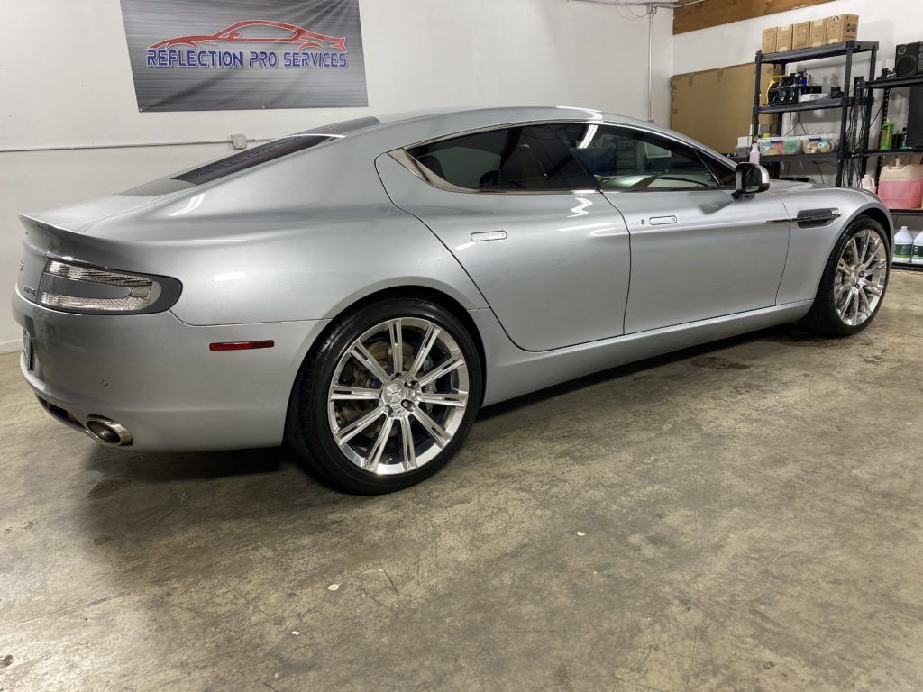 A silver aston martin sports car is parked in a garage.