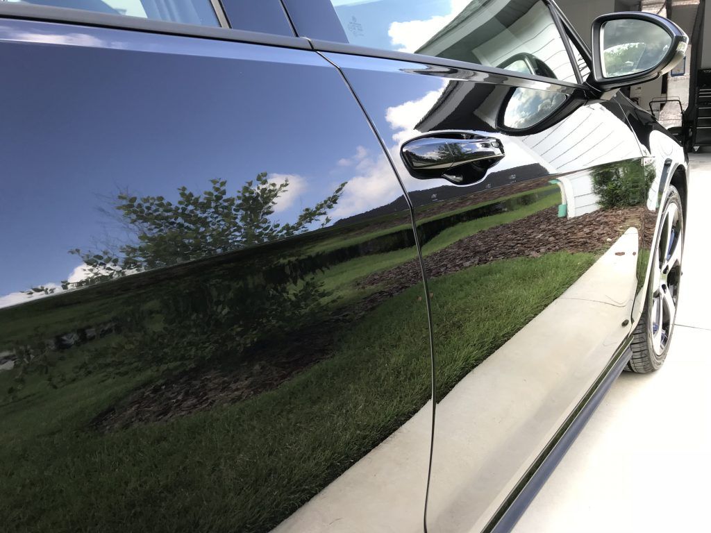 A black car is parked in a driveway in front of a house.