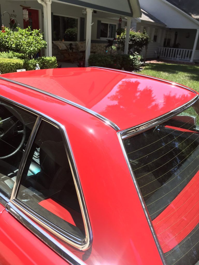 A red car is parked in front of a house
