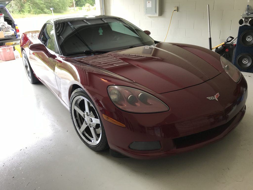 A red corvette is parked in a garage.