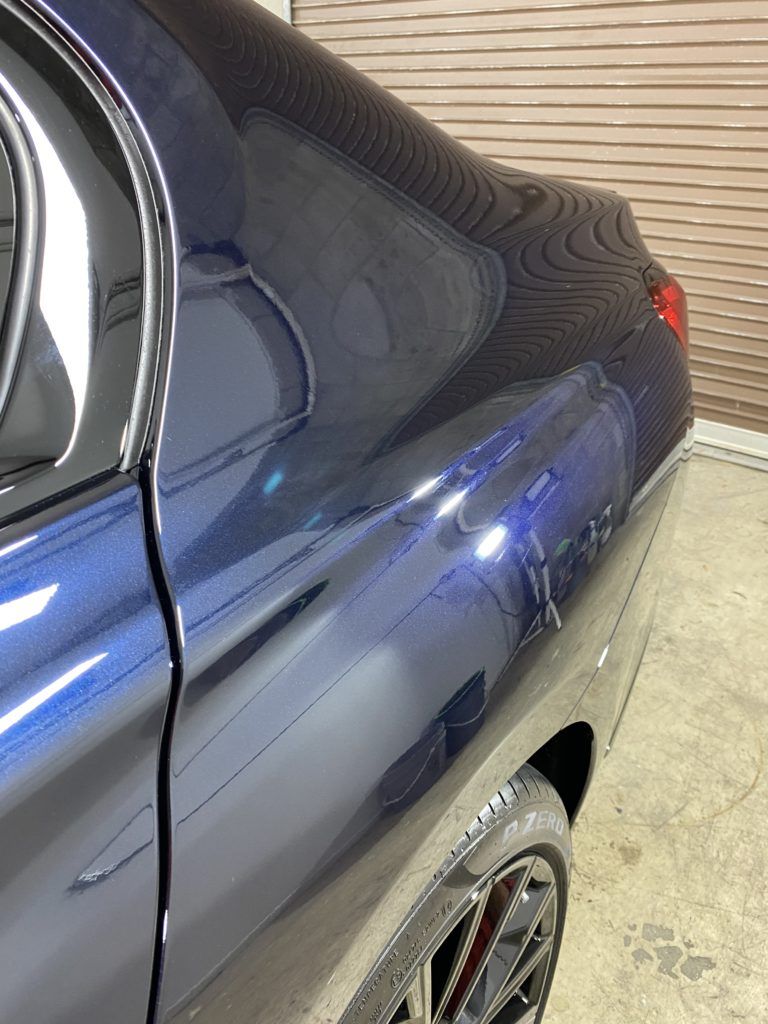 A blue car is parked in a garage next to a garage door.