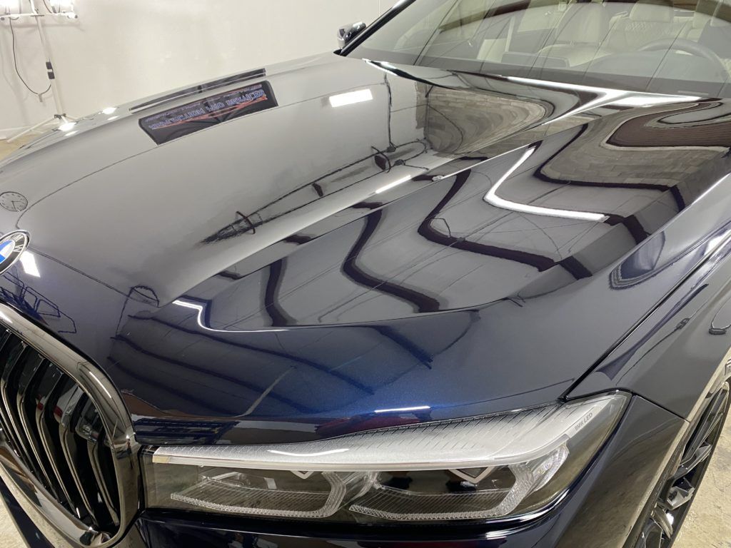 A close up of a car 's hood and headlights in a garage.