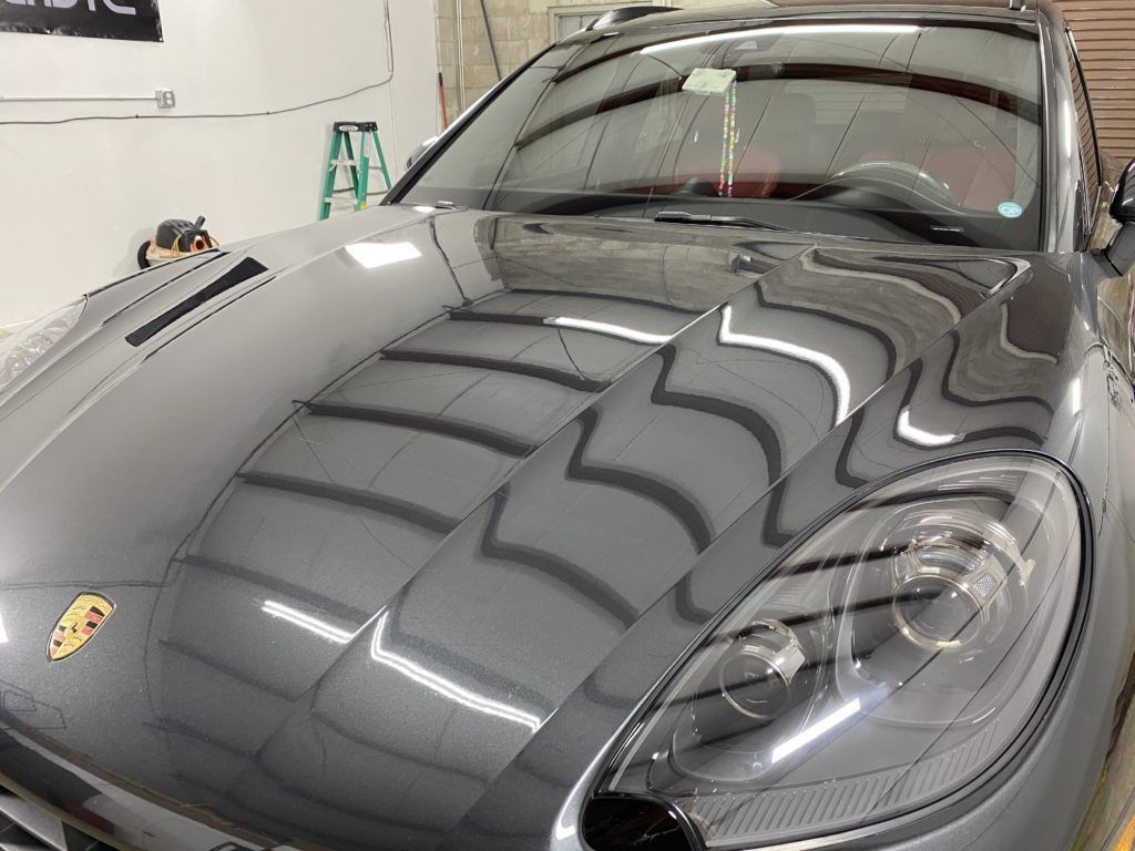 A gray porsche macan is parked in a garage.