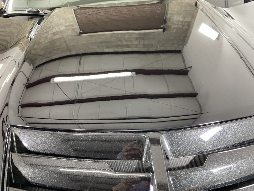 The hood of a car is reflected in a mirror.