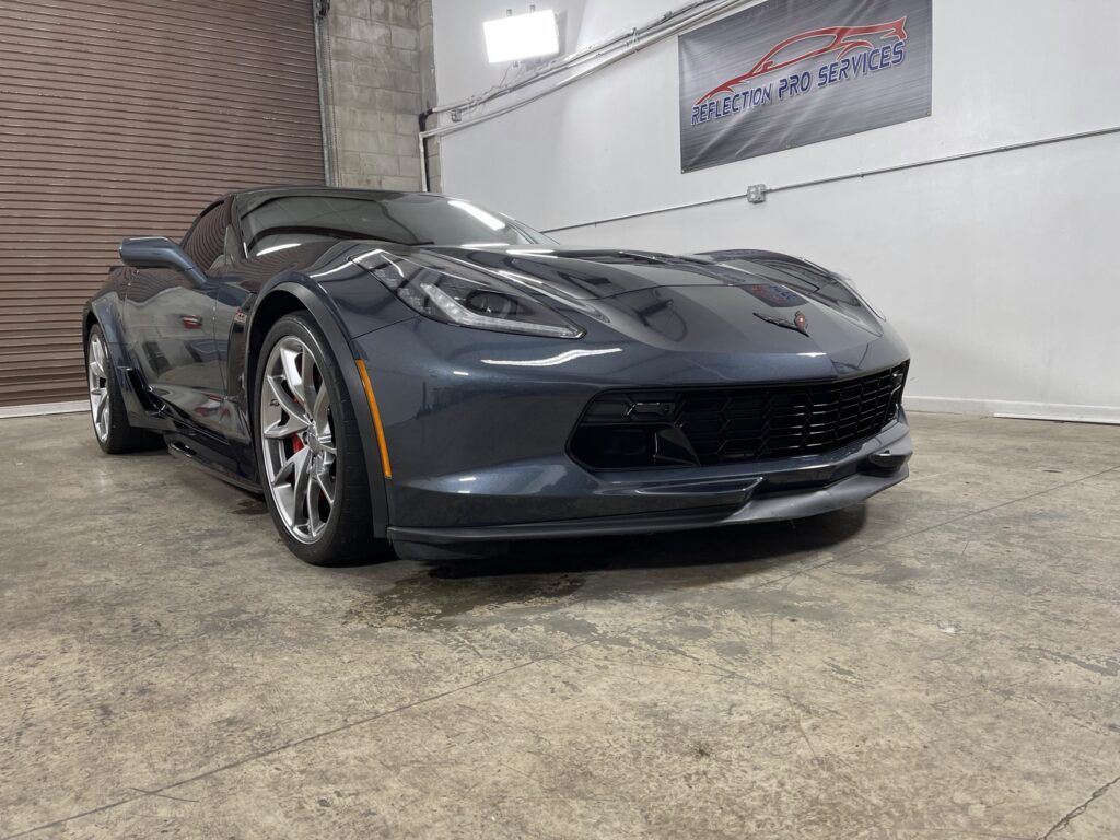 A gray sports car is parked in a garage.