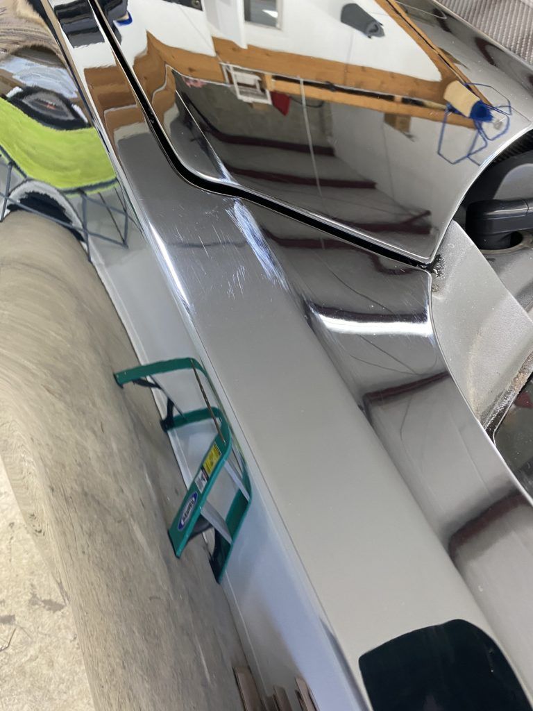 A ladder is sitting next to a mirror in a garage.