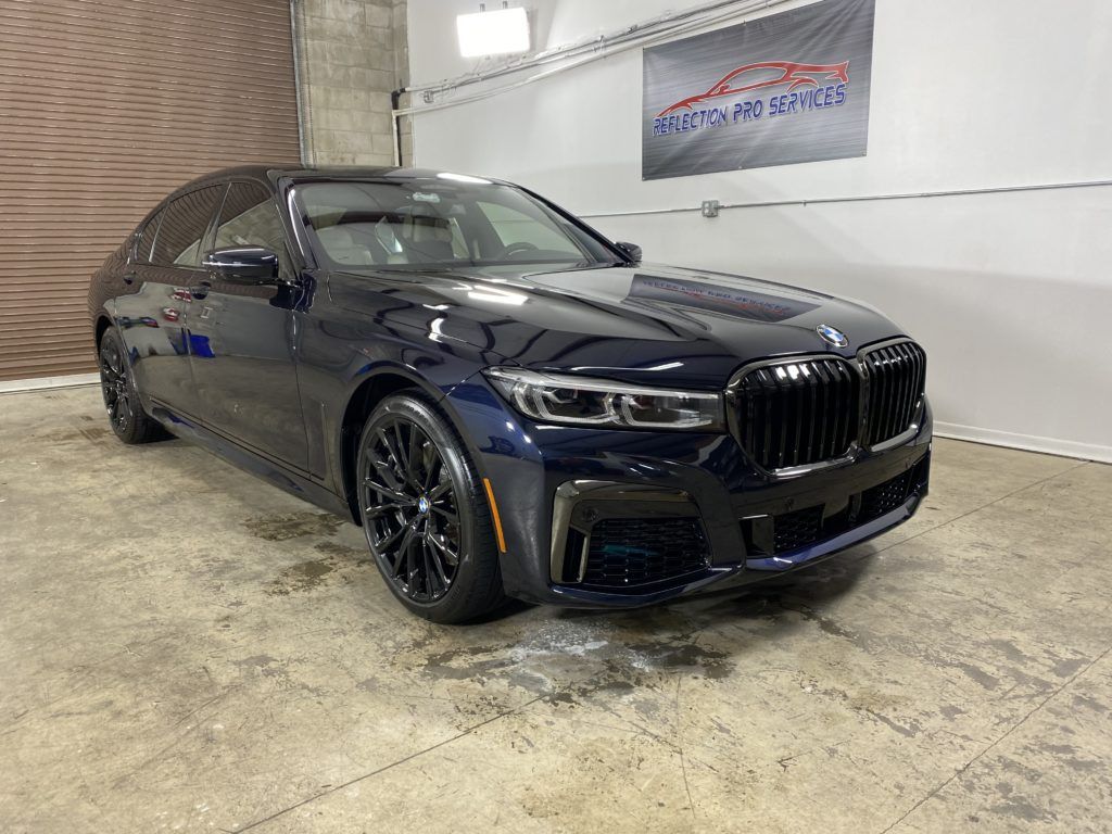 A black bmw 7 series is parked in a garage.