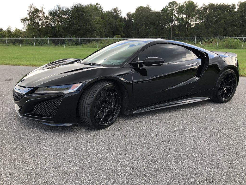 A black sports car is parked on the side of the road.