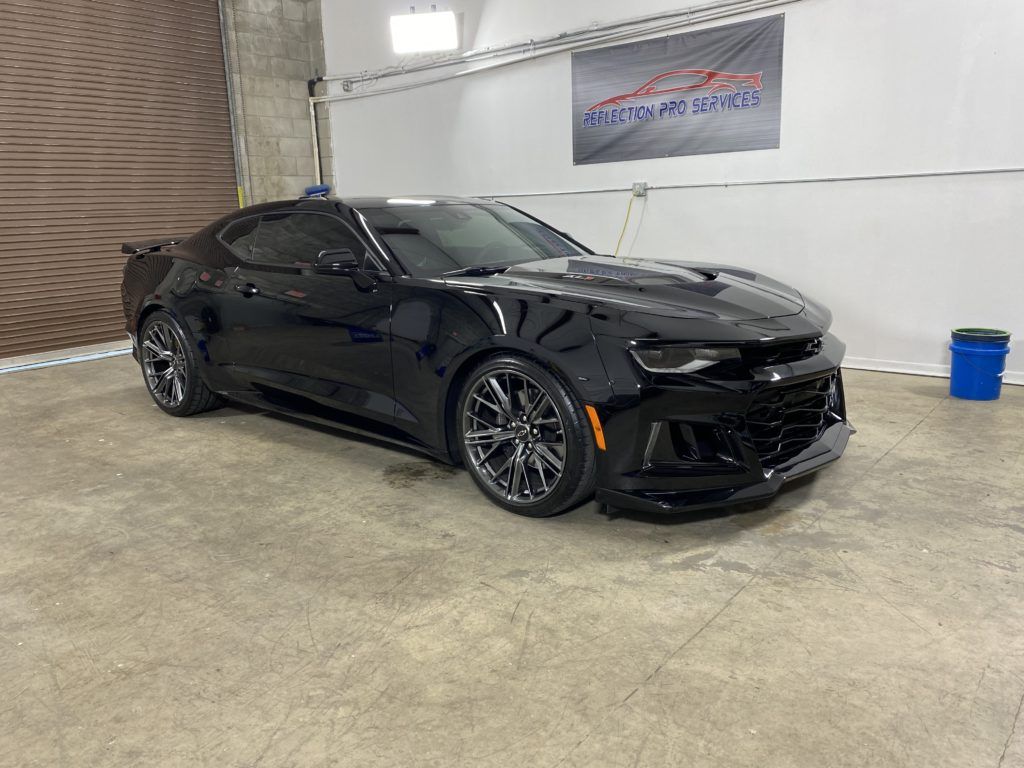 A black chevrolet camaro zl1 is parked in a garage.