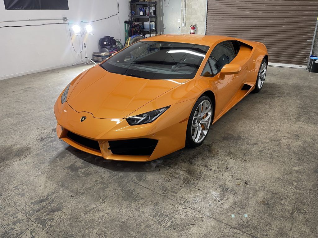 An orange lamborghini huracan is parked in a garage.