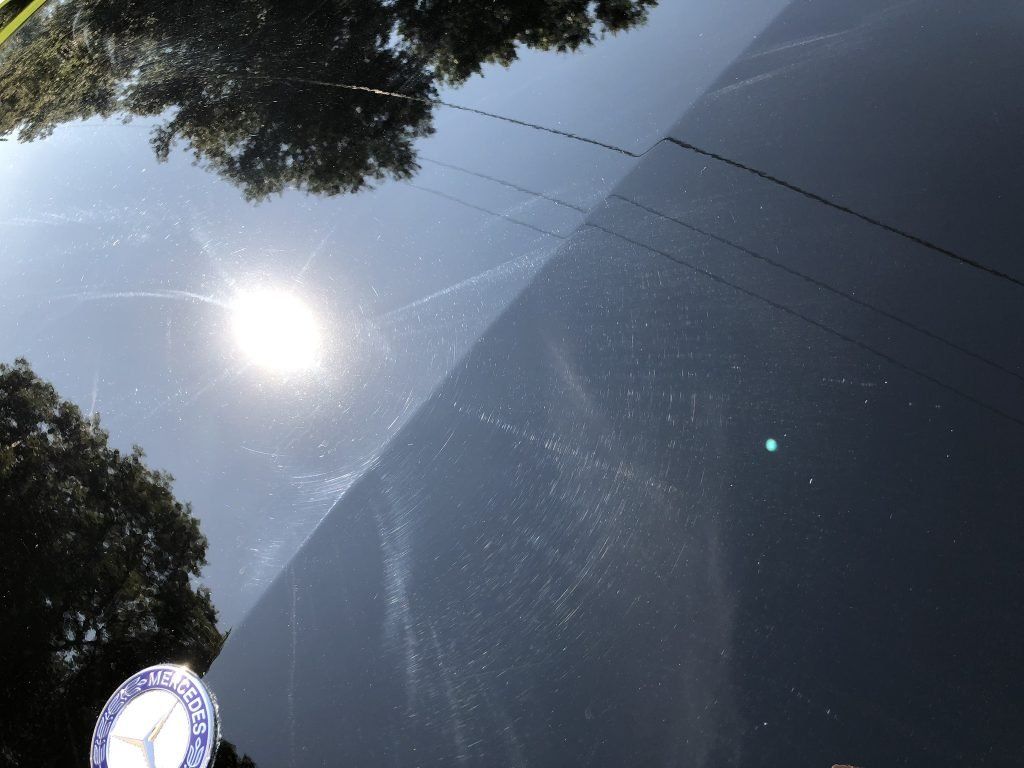 The sun is reflected in the windshield of a car
