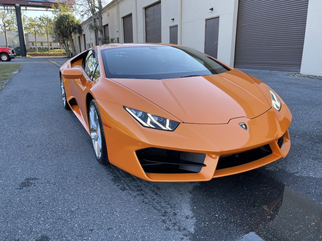 An orange lamborghini huracan is parked in front of a garage.