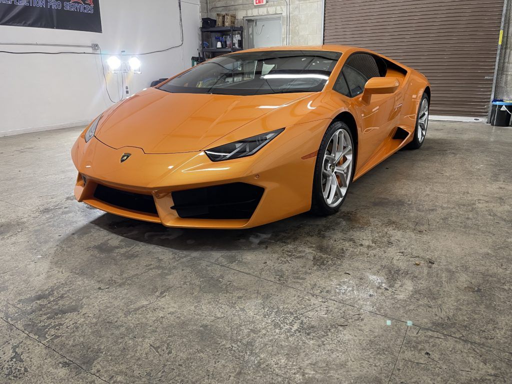 An orange lamborghini huracan is parked in a garage.