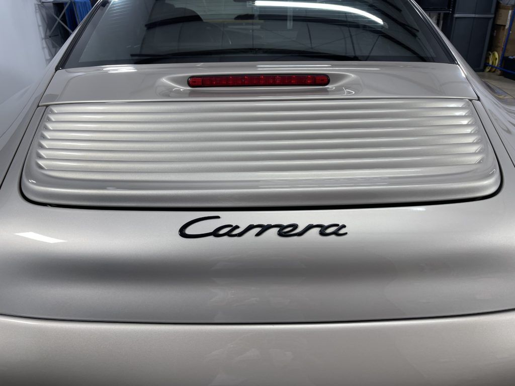 A silver porsche carrera is parked in a garage