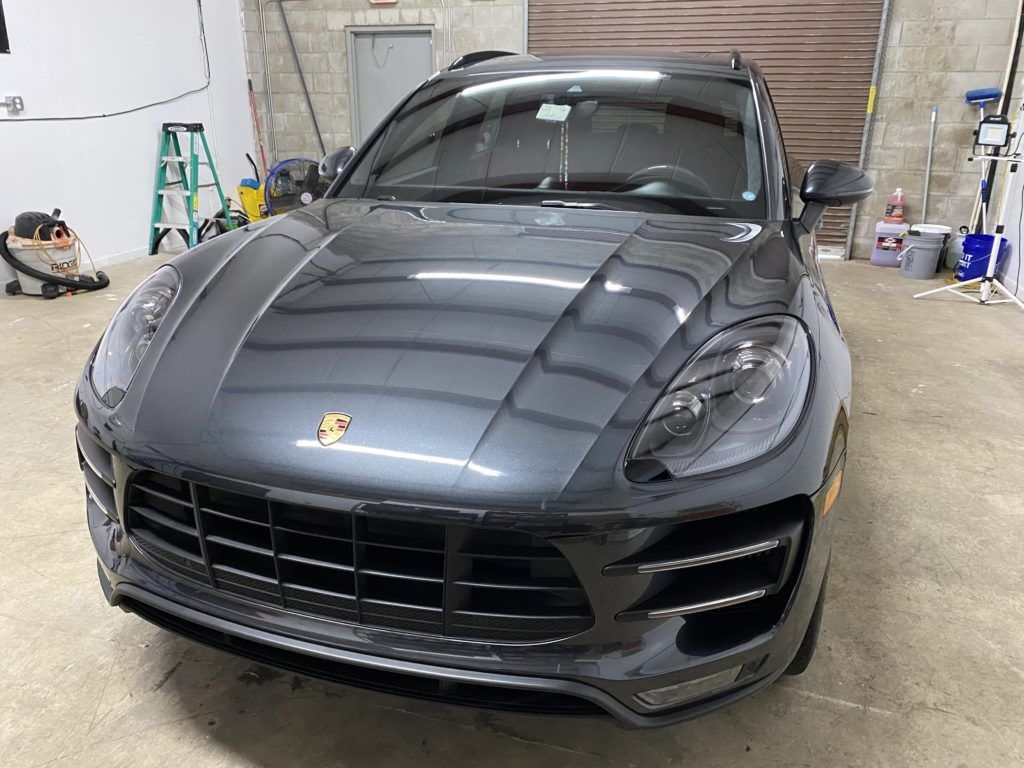 A gray porsche macan is parked in a garage.