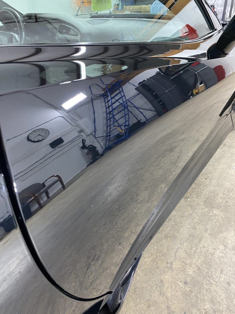 A close up of a car door with a reflection of a building in it.