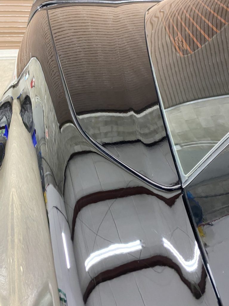 A close up of a car 's hood with a reflection of a building in the mirror.