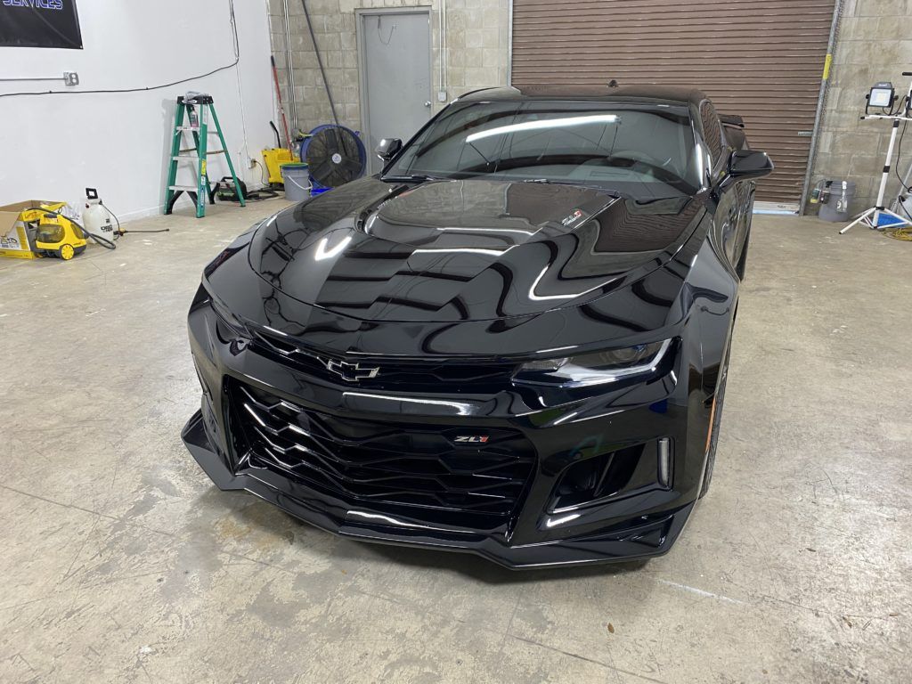A black chevrolet camaro zl1 is parked in a garage.