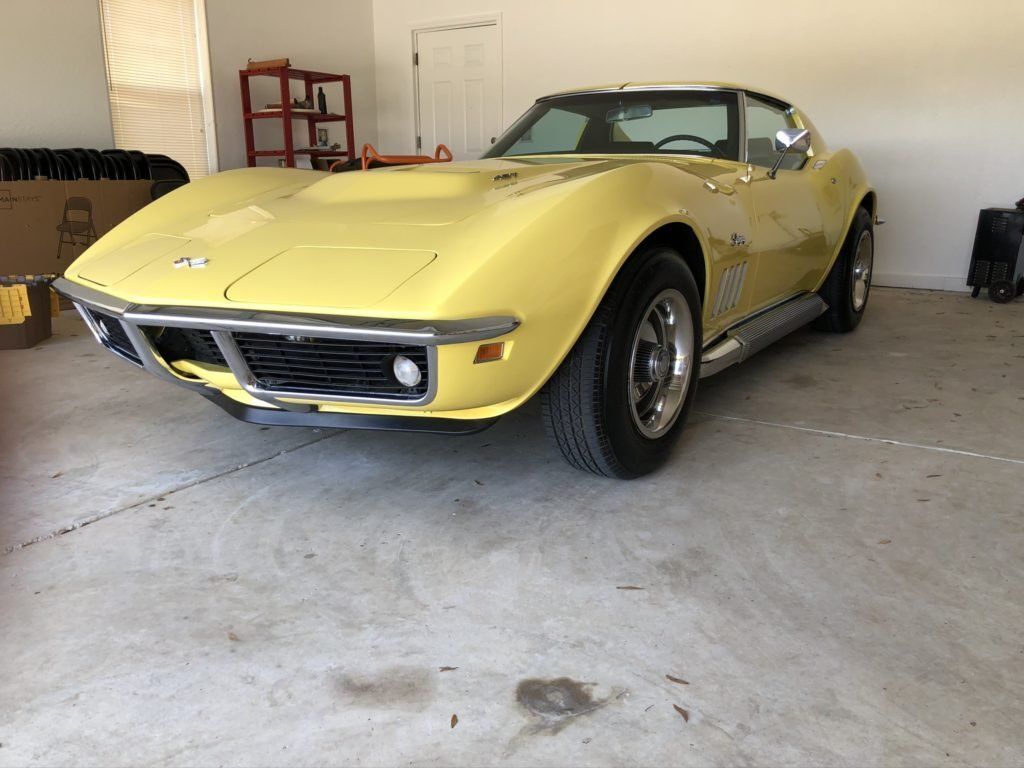 A yellow corvette is parked in a garage.