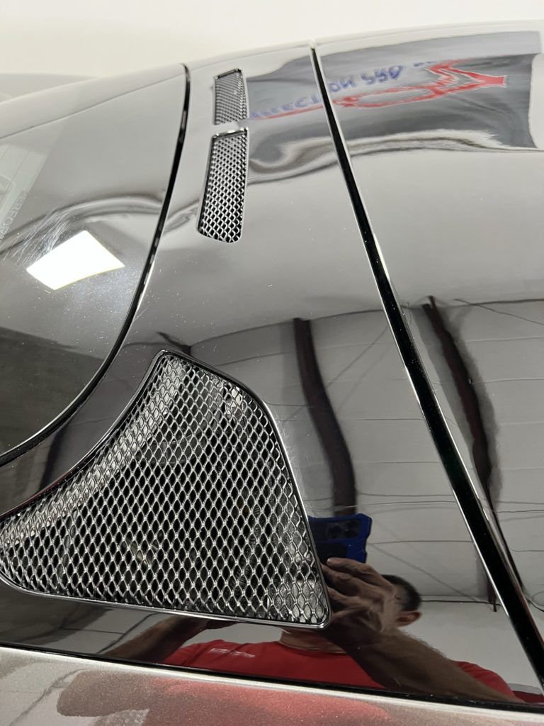 A man is taking a picture of his reflection in a car window