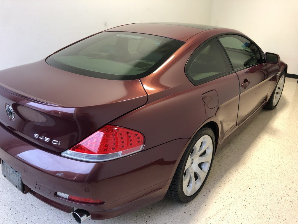 A burgundy bmw is parked in a garage.