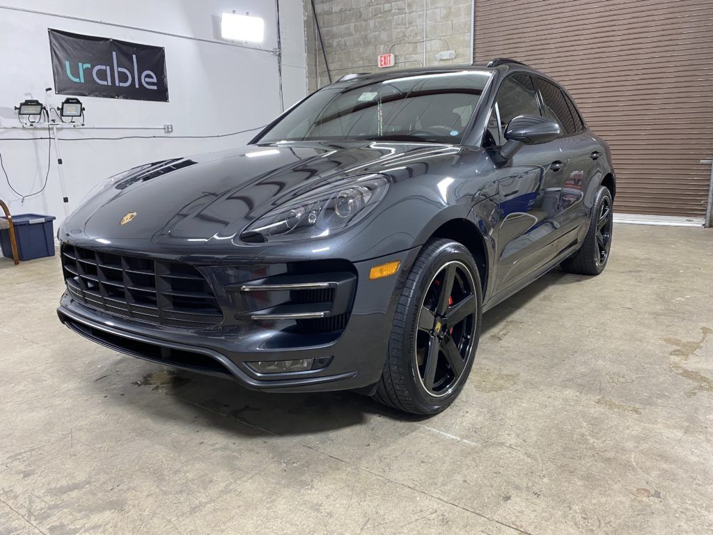 A black porsche macan turbo is parked in a garage.