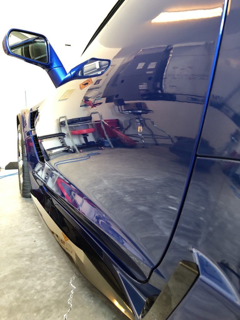 A blue sports car is parked in a garage