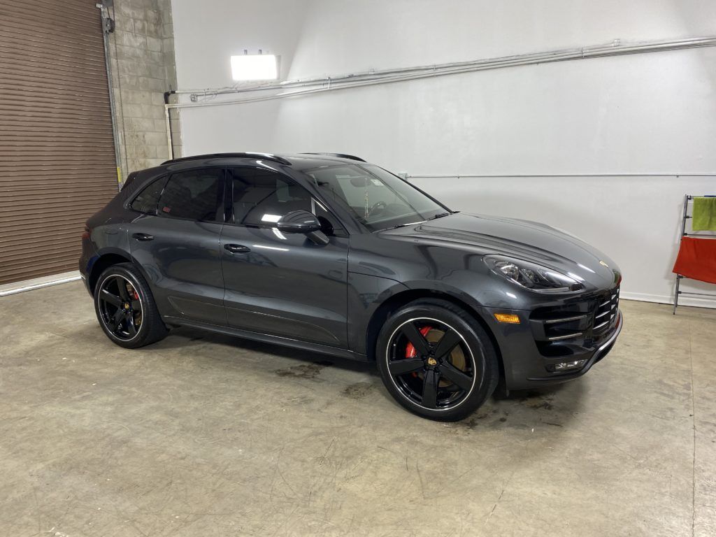 A gray porsche macan turbo is parked in a garage.