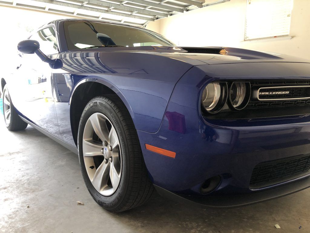 A blue dodge challenger is parked in a garage.