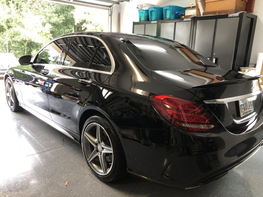A black mercedes benz is parked in a garage.