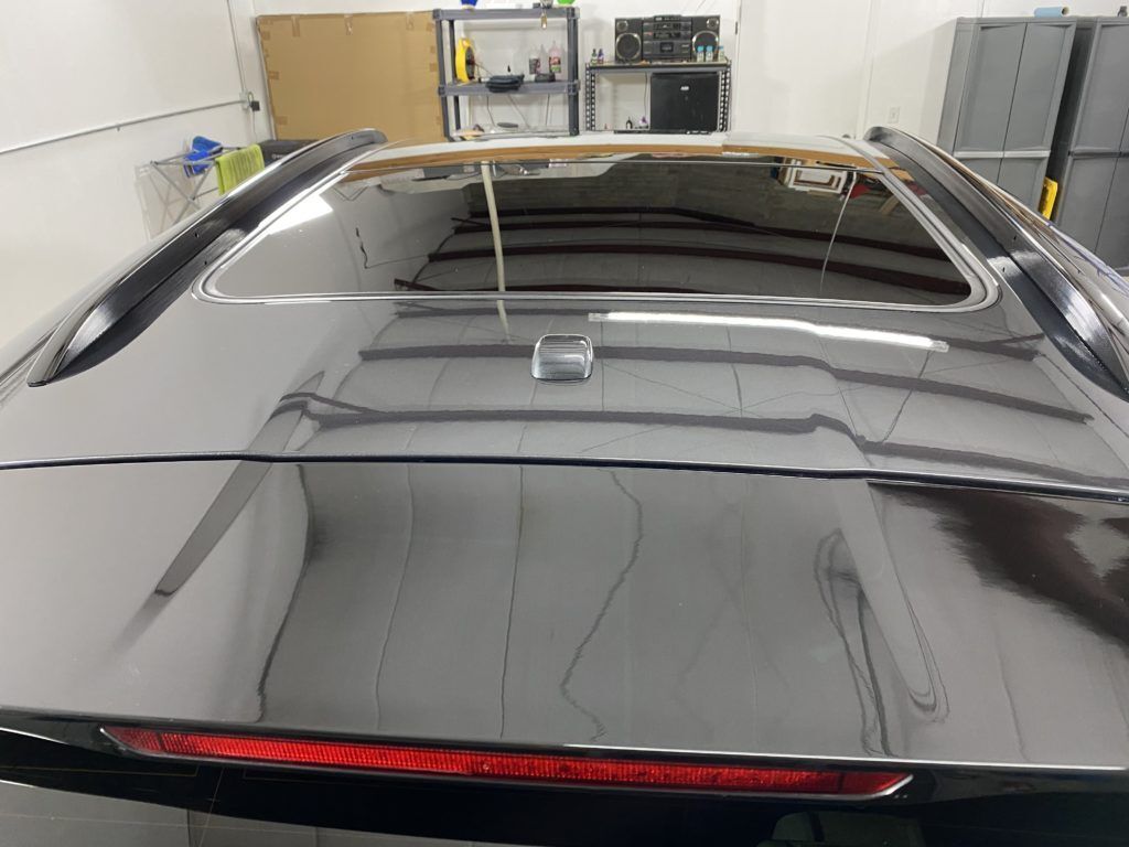 A black car is parked in a garage with the roof open.