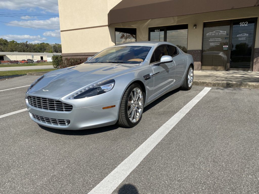 A silver sports car is parked in a parking lot in front of a building.