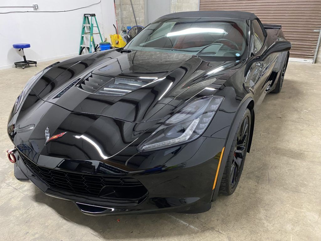 A black corvette convertible is parked in a garage.