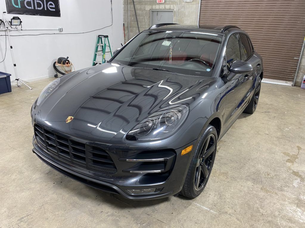 A gray porsche macan turbo is parked in a garage.