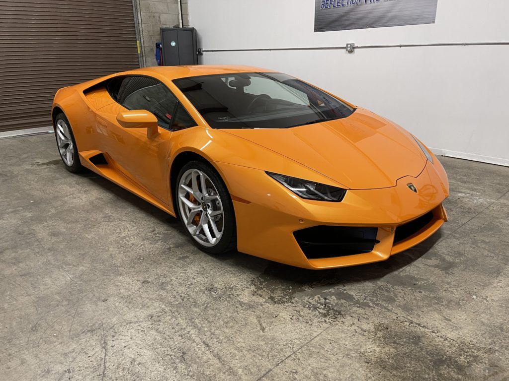 An orange lamborghini huracan is parked in a garage.