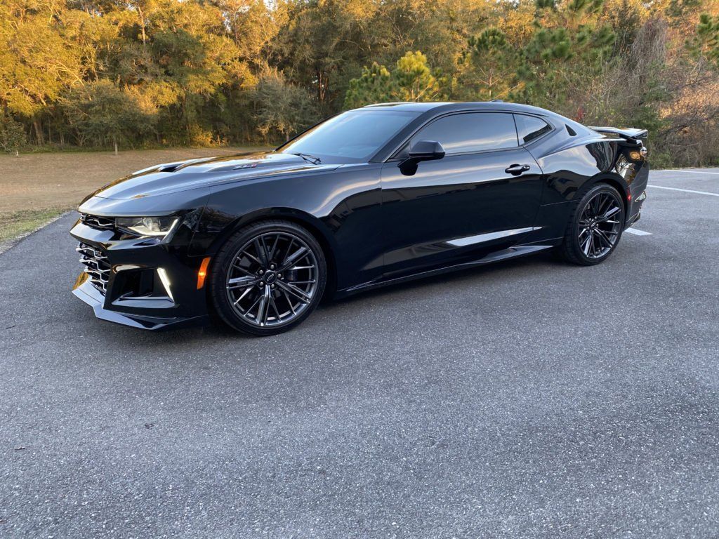 A black chevrolet camaro is parked on the side of the road.
