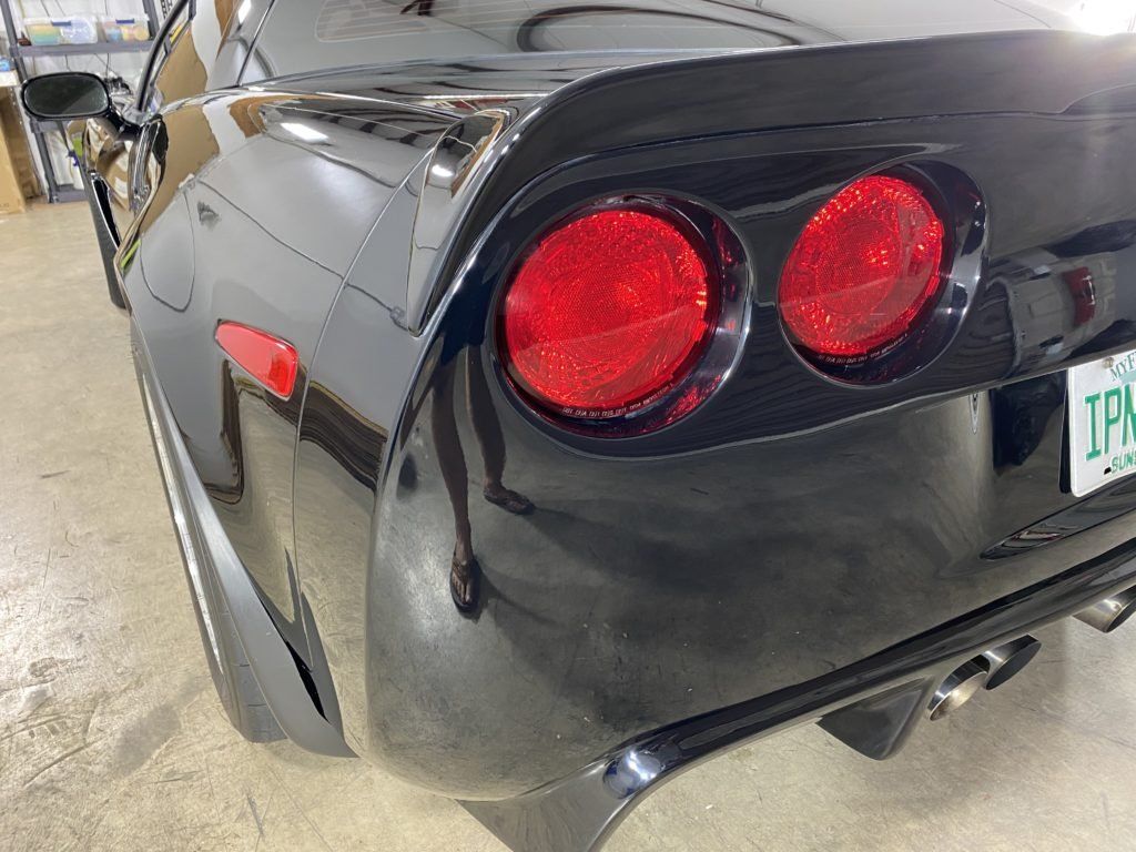 A black sports car with a license plate that says ipk is parked in a garage.