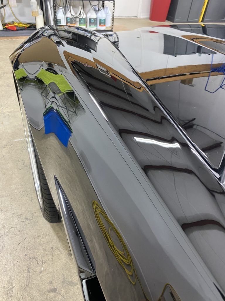 A close up of a car 's hood in a garage.