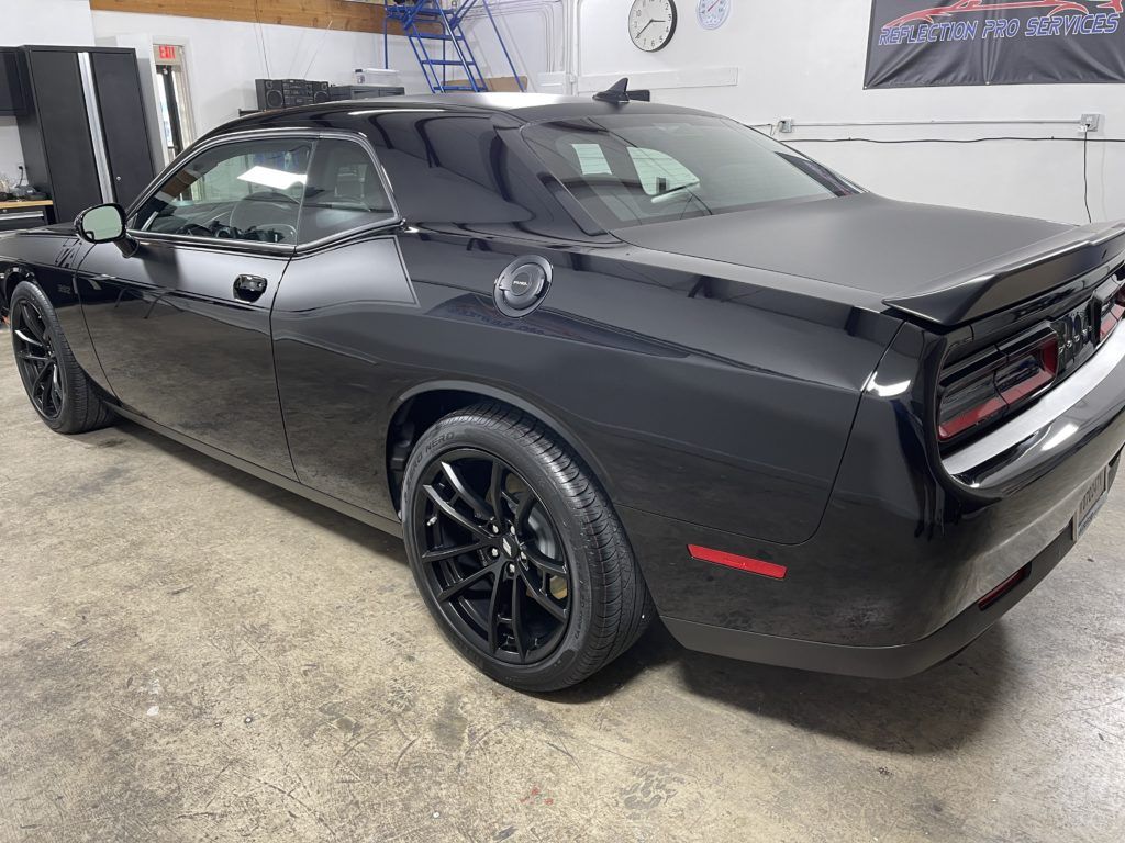 A black dodge challenger is parked in a garage.