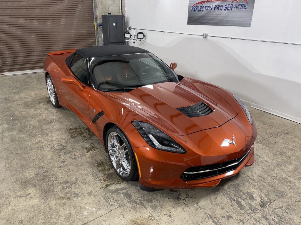 A red corvette convertible is parked in a garage.
