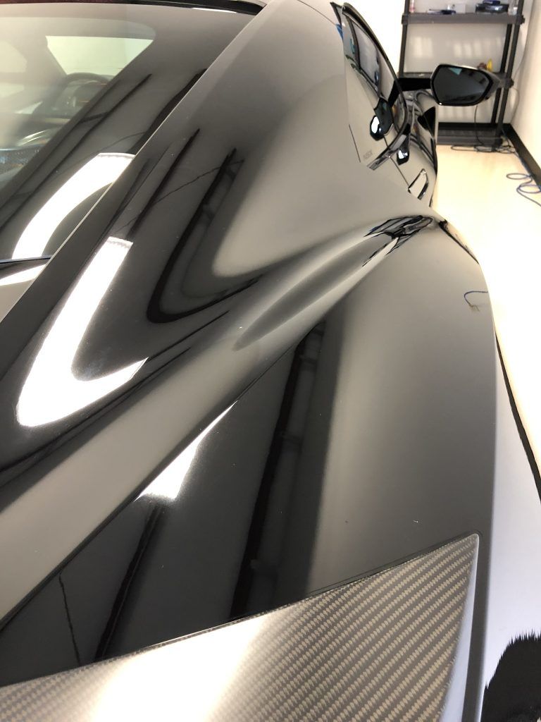 A black sports car is parked in a garage