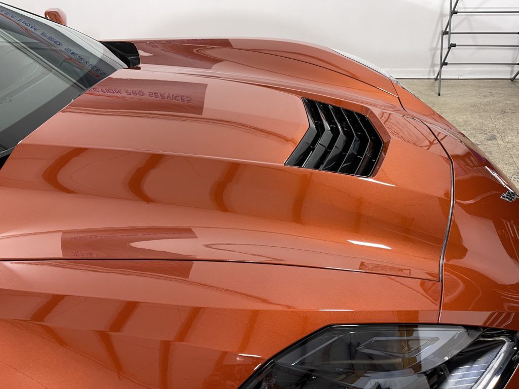 A close up of the hood of an orange sports car