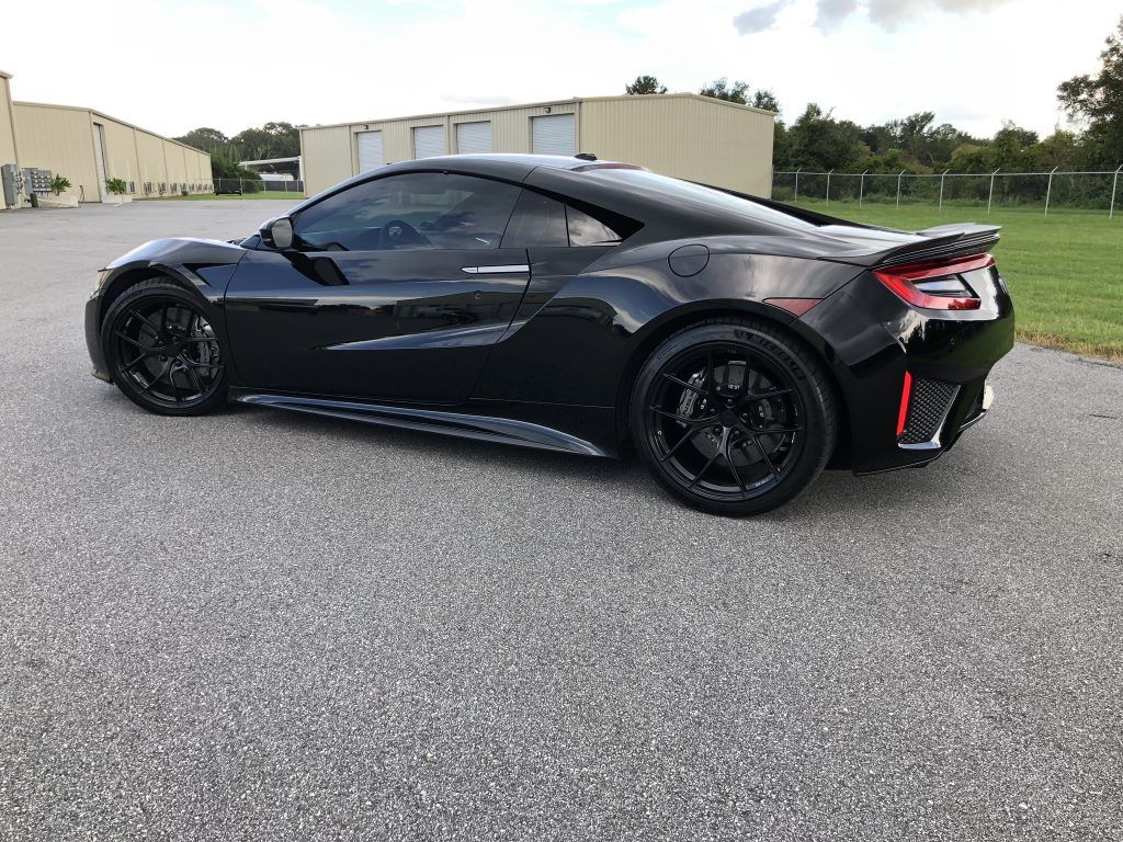 A black sports car is parked in a parking lot.