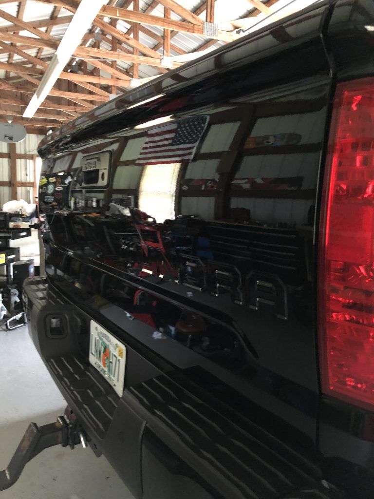 A black truck with an american flag on the back is parked in a garage.