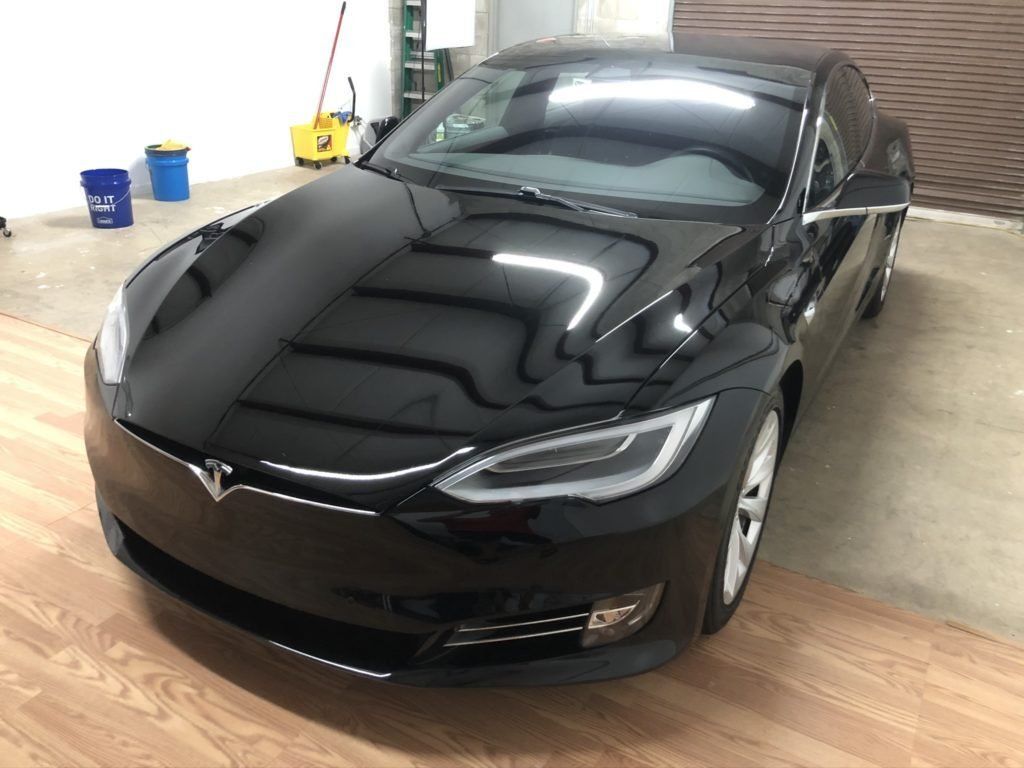 A black tesla model s is parked in a garage.