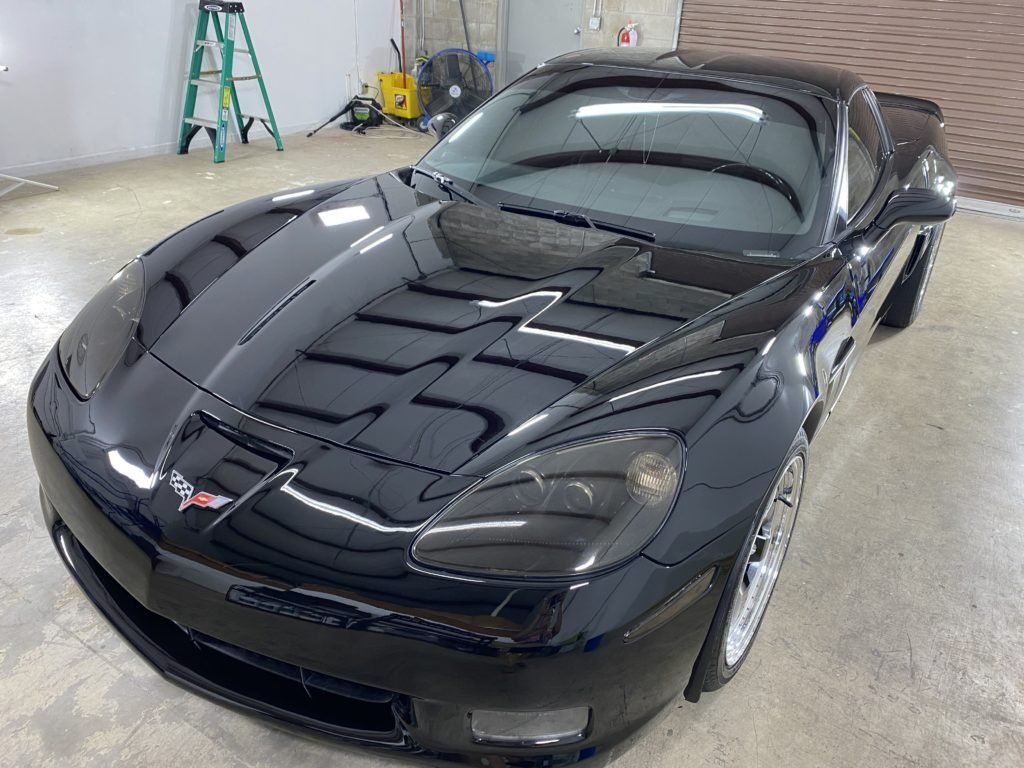 A black sports car is parked in a garage next to a ladder.