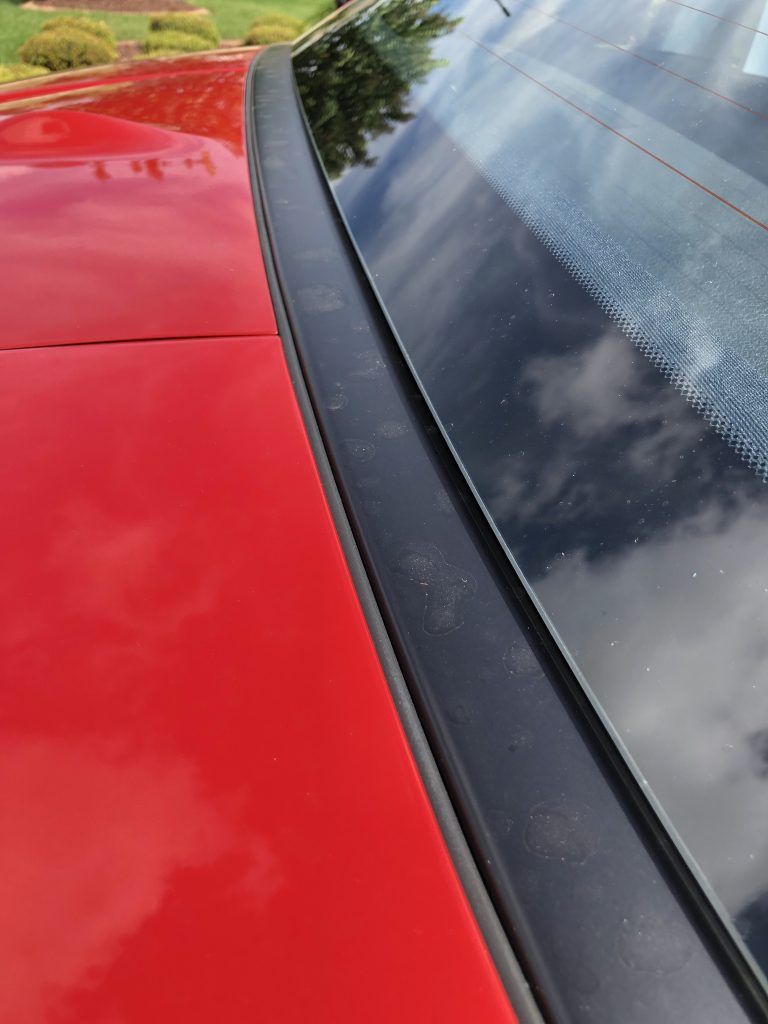 A red car with a black trim on the windshield