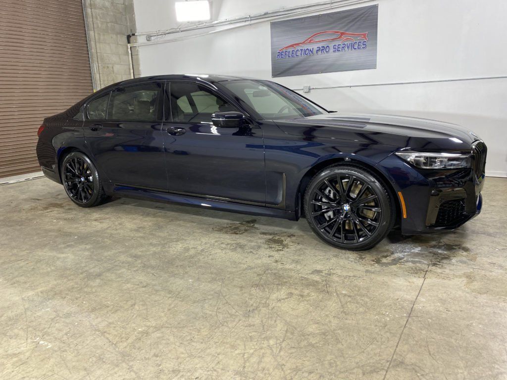 A black bmw 750li is parked in a garage.