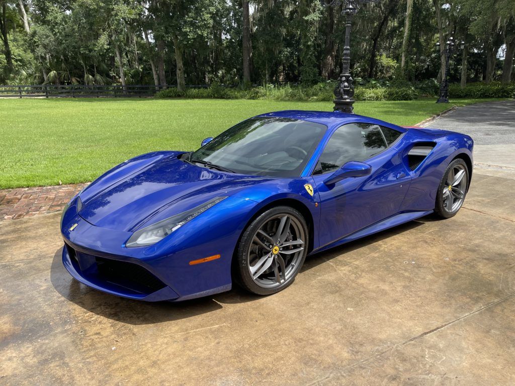 A blue ferrari 488 gtb is parked in a driveway.