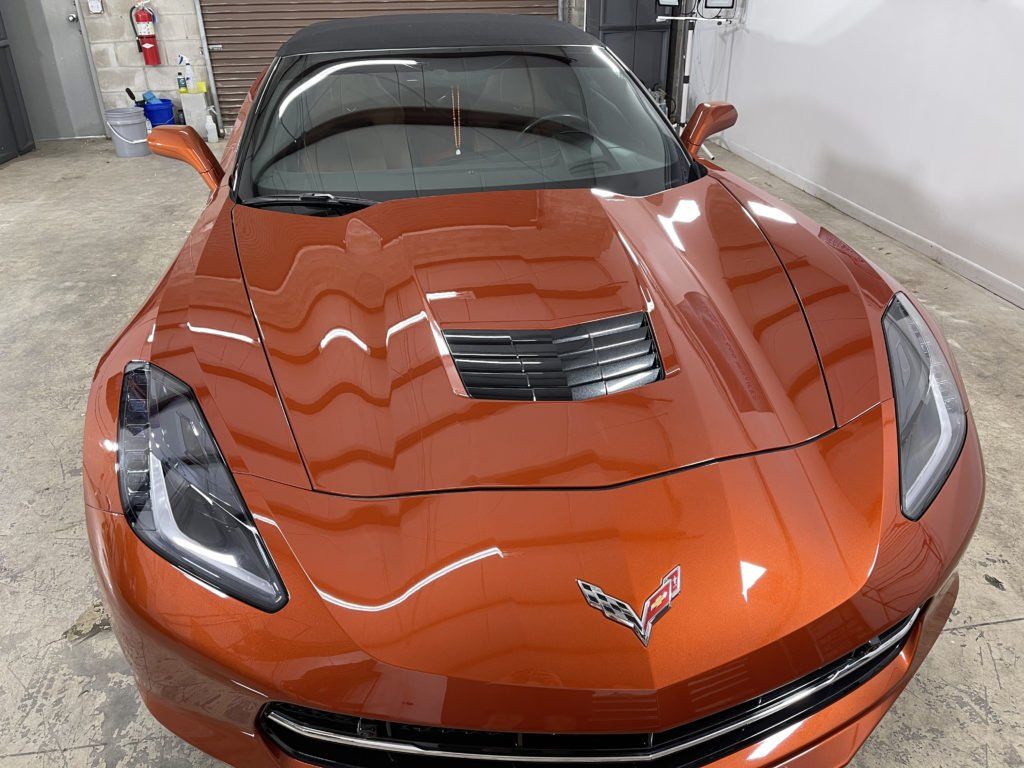 A red corvette convertible is parked in a garage.